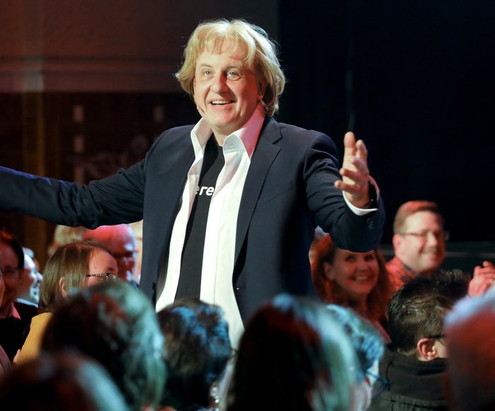 Der Künstler steht mit ausgebreiteten Armen im Publikum.