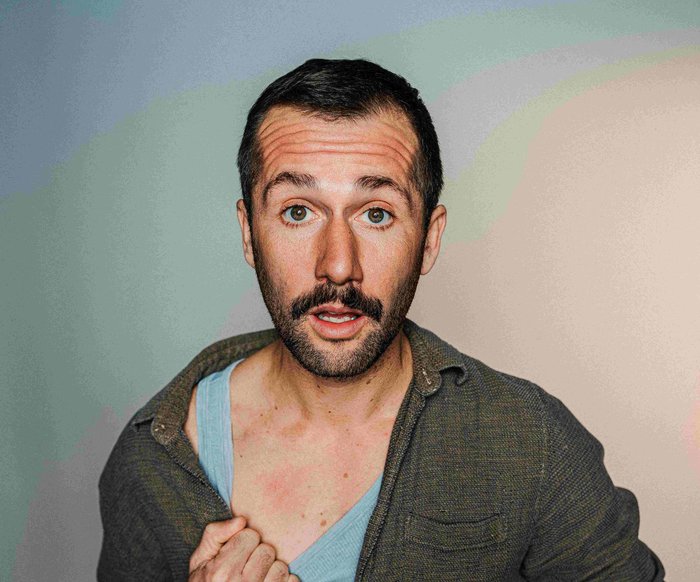 Portraitfoto von Stefan Leonhardsberger. Er schaut mit geöffnetem Mund in die Kamera, er trägt ein grünes Hemd, darunter ist ein blaues Unterhemd zu sehen.