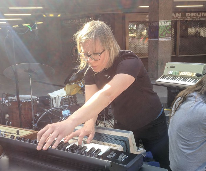 Komponistin arbeitet live an einem Mischpult und Keyboard in einem Studio- oder Proberaum.