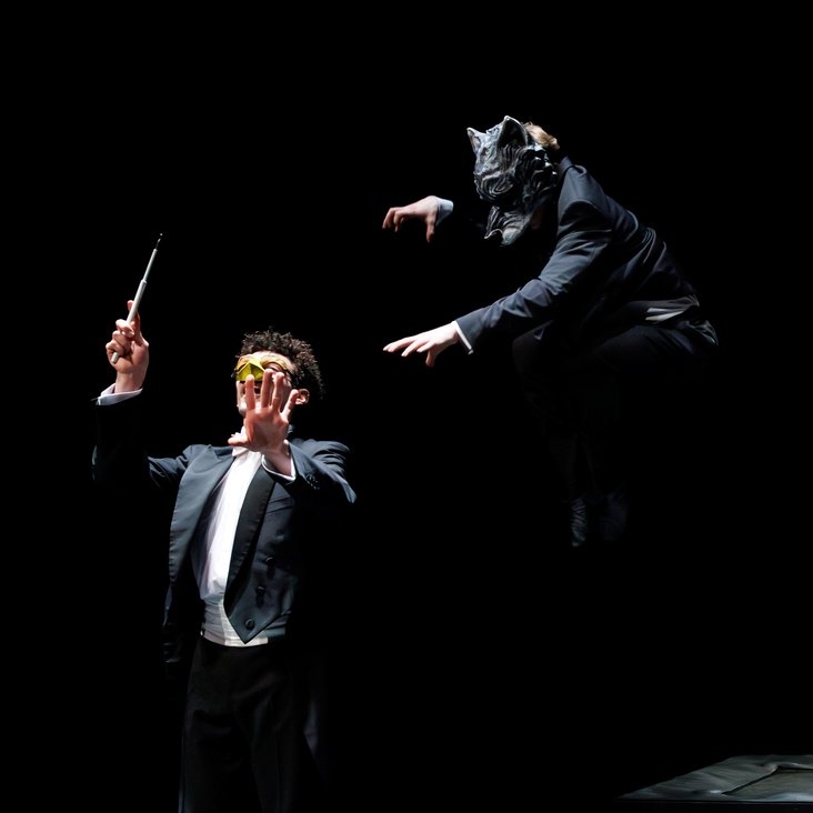 Tänzer:innen in Kostüm auf der Bühne, der Boden ist schwarz und die Bühne ist professionell ausgeleuchtet.