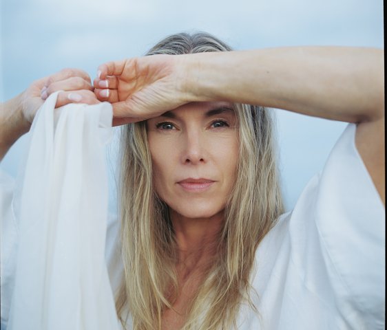 Rebekka Bakken mit langen blonden Haaren und weißer Kleidung hält sich die Hand an die Stirm