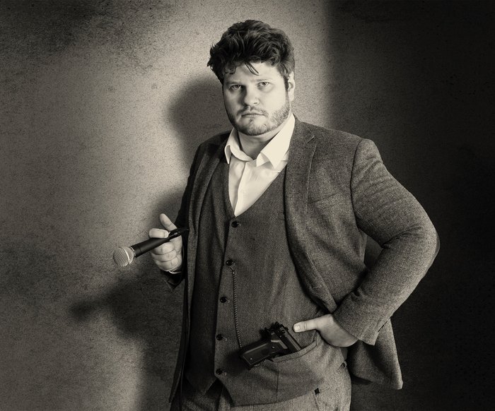 Jan Philipp Zymny im Anzug mit Zigarre in der Hand und Pistole in der Tasche