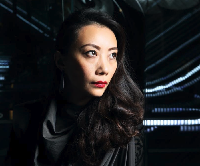 Porträt einer Frau in moderner Architektur mit Lichtlinien, nachdenklicher Blick in die Ferne.