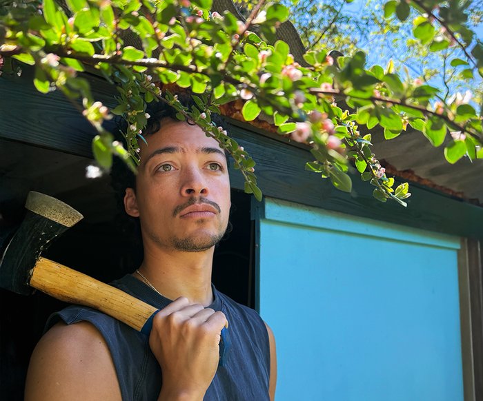Aurel Mertz in ärmellosem T-Shirt und ein Beil in der Hand, das er über die Schulter gelegt hat.